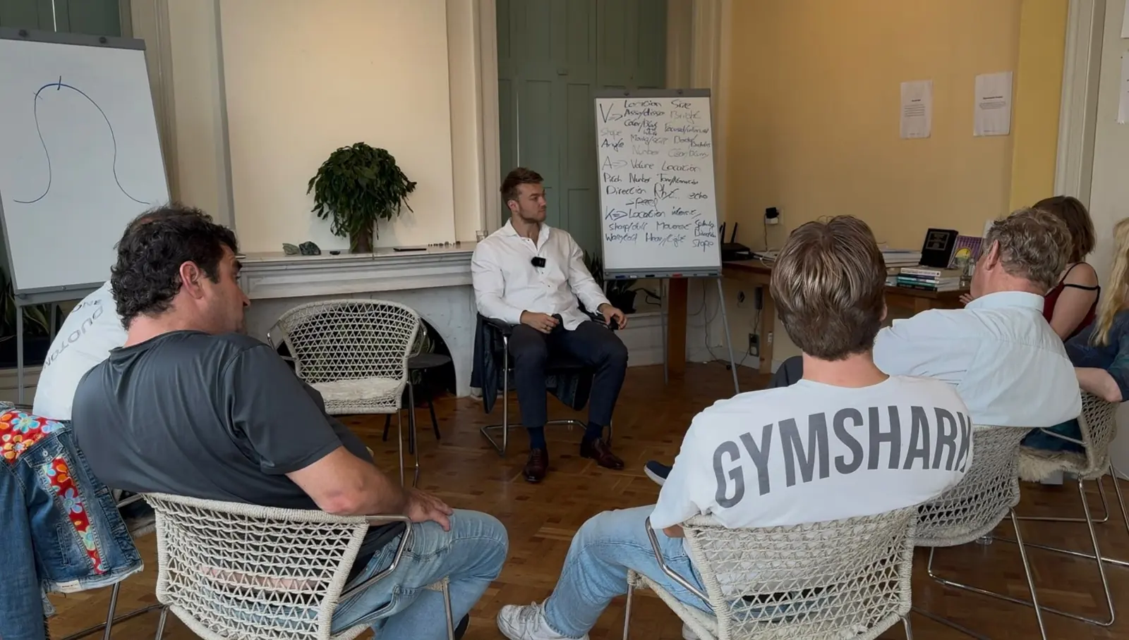 The group seated in a circle while the trainer works at the flipchart